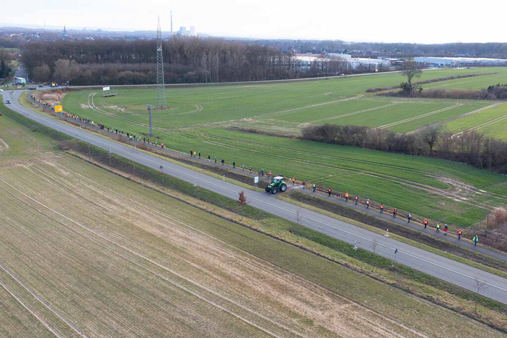 Links auf dem Foto ist ein Ausschnitt des Gebietes, das für ein neues Gewerbegebiet herhalten soll. Die Menschenkette demonstrierte die Länge der westlichen Ausdehnung. Foto: Kreativshooting/T. Schütte